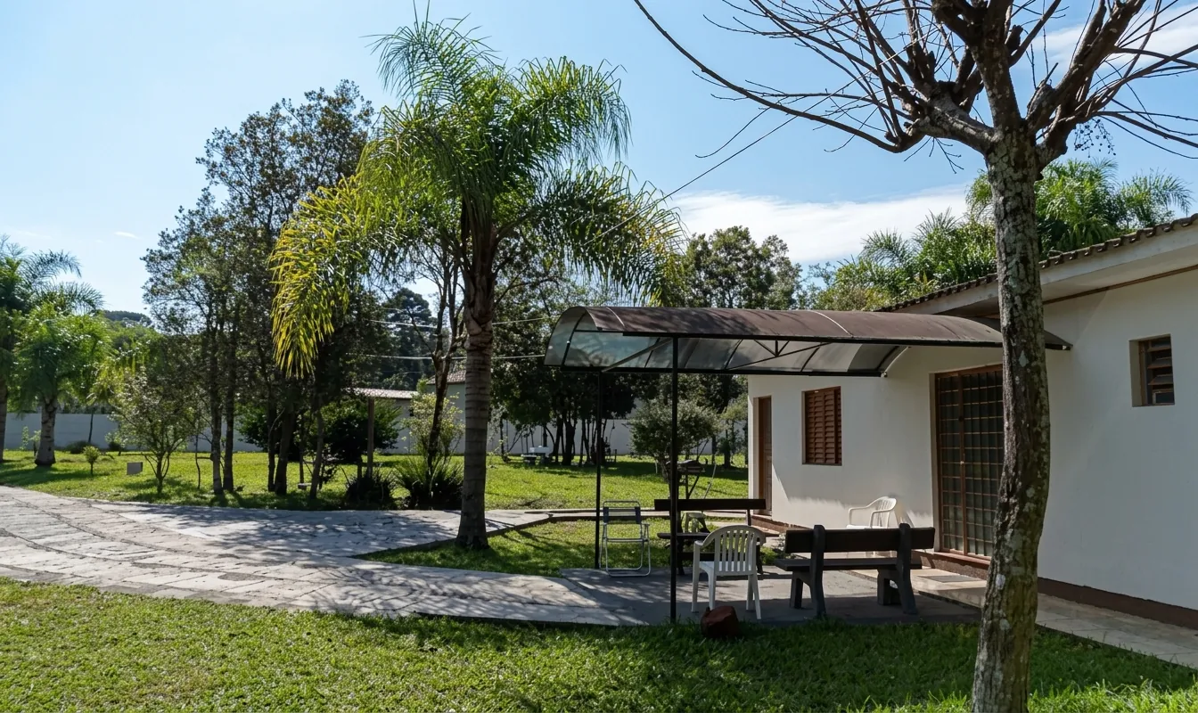 Varanda coberta com mesa, bancos e cadeiras ao lado do gramado